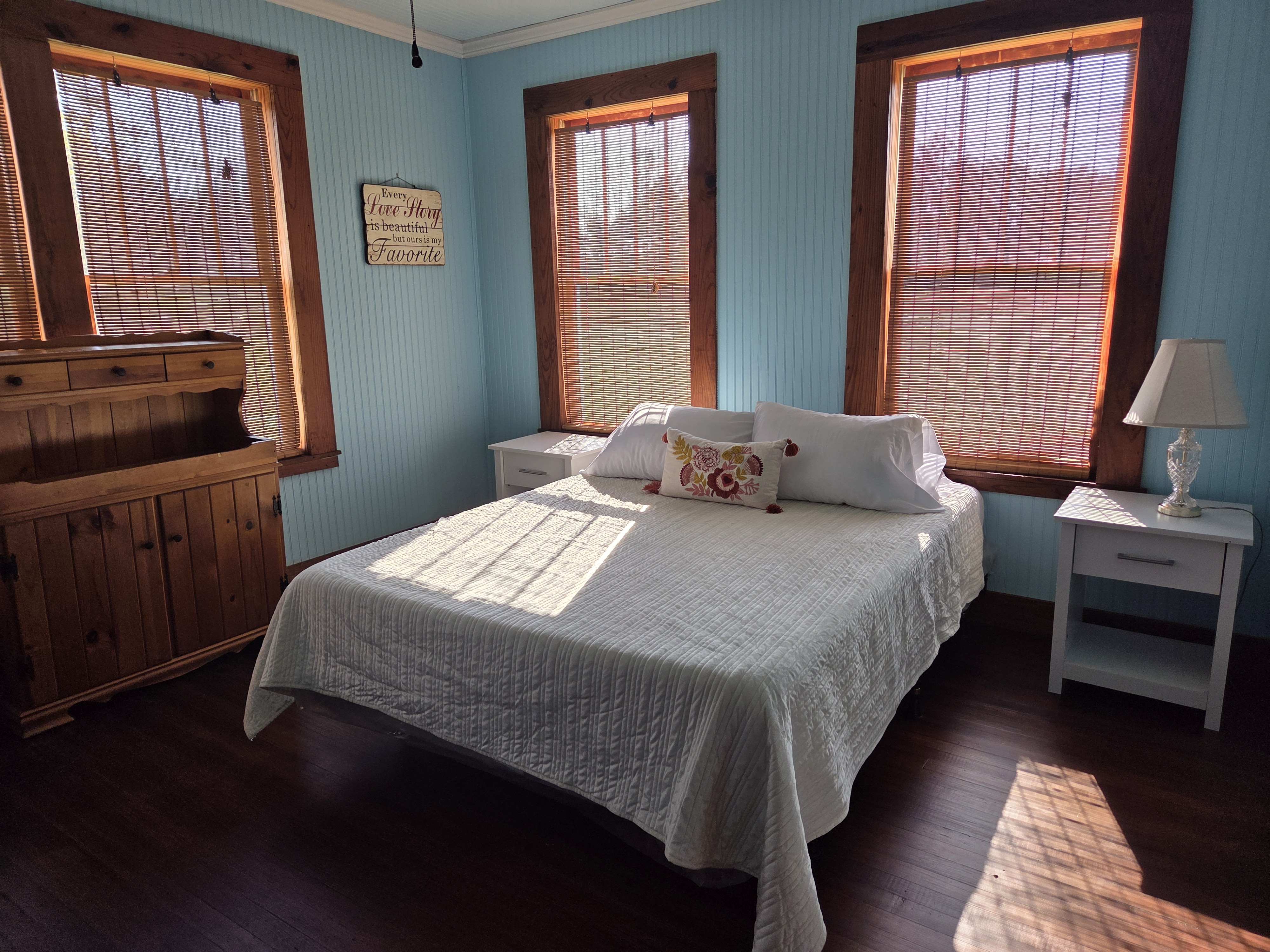 Sunlit bedroom with morning light through farmhouse windows