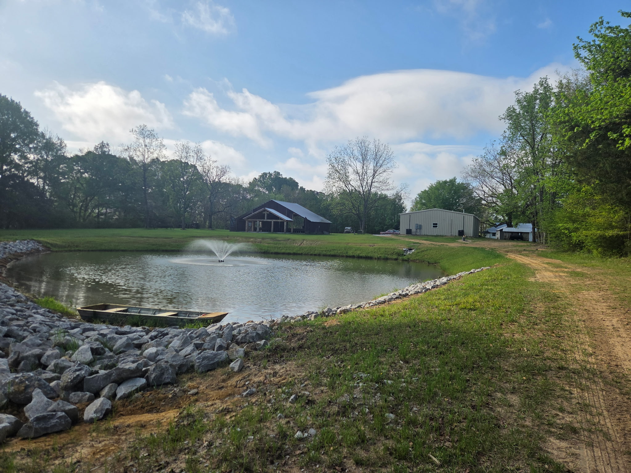 Pond, fountain, and open acres with the pavilion beyond the tree line